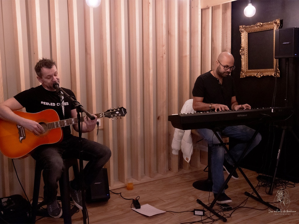 Deux musiciens en live – guitare et clavier – créent une ambiance chaleureuse et détendue lors d’une soirée Bo Réso dans un lieu cosy et intimiste.